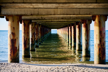 Obraz premium Rusty pier columns over Baltic Sea waters at sunset