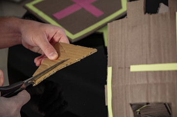 Male hands cutting cardboard crafts with scissors. Concept of DIY, handmade creativity, art therapy, craft making, imagination, and creative process at home. © Evgeniya