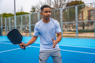 Young man playing pickleball on outdoor court