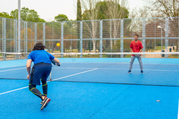 Obraz premium People playing pickleball on a blue outdoor court