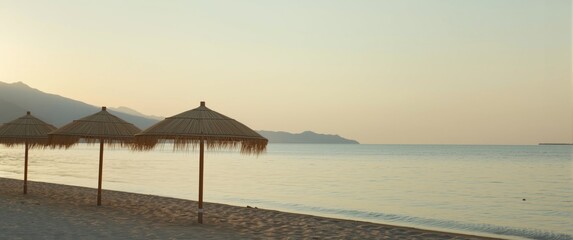 Obraz premium Summer sunrise at Vrasna Beach, Greece featuring reed parasols and selective focus