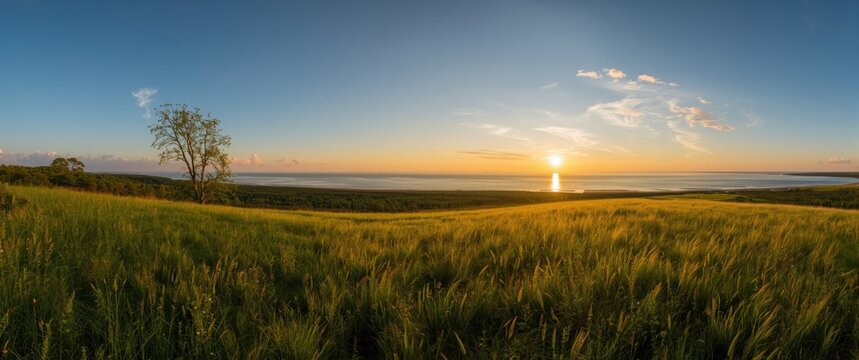 Breathtaking panoramic vista of the Baltic Sea seen from the viewpoint, featuring a meadow illuminated by sunset, with forest and sea beyond