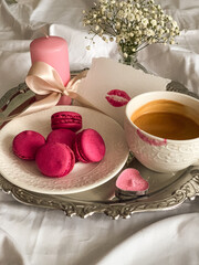 Pink macarons on a white plate and flowers. Valentine`s Day aesthetic