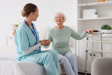 Obraz premium Nurse and senior woman sitting on bed