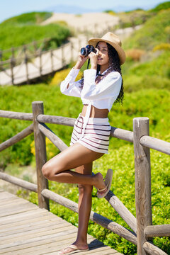 A Young Woman is Enjoying a Beautiful Summer Day at the Beach while Taking Pictures with Her Camera