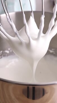 Vertical Video of a Stand Mixer Whisking Cream or Egg Whites in a Stainless Steel Bowl, Creating Frothy Whipped Peaks for Baking and Dessert Preparati