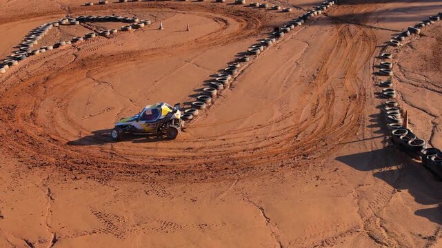 Off-road Racing Buggy Drifting On A Dirt Track With Rows And Stacks Of Tires. - aerial shot