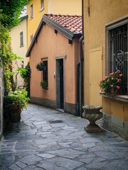 Bellagio,Italy - October 26,2025: paving stones street with old yellow houses, vases, flowers © Kseniia