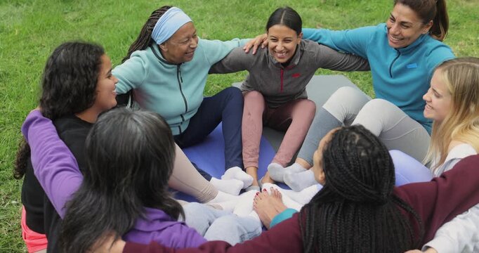 Women's circle having fun hugging each other during yoga class outdoor - Happy people of different age and body types - Healthy lifestyle, multiracial group and meditation concept