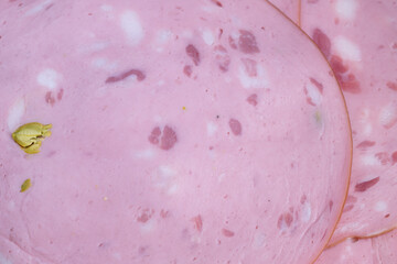 Processed sausage slices with pistachio inclusions, closeup suggesting industrial slicing and quality control, uniform rounds ready for packaging and bulk distribution