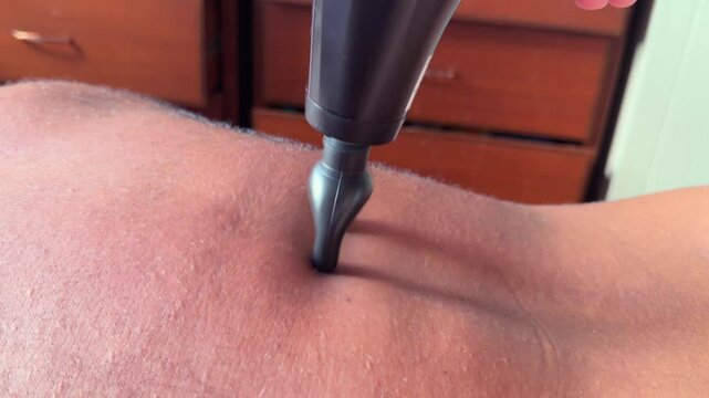 Slow motion of home back body massage with massage gun with U-shaped head, Mahe, Seychelles 25fps 001