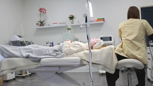 Johvi, Estonia &ndash; December 24, 2026: A woman undergoes an IPL facial cosmetic procedure using light-based aesthetic equipment in a beauty clinic. Real clinical environment during a professional cosmeto