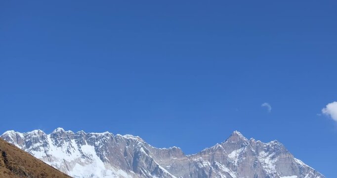 Pan-down aerial drone shot revealing Mount Everest and Ama Dablam along with Shomare village. High-altitude residential settlement located on the Everest Base Camp trek route in Nepal.