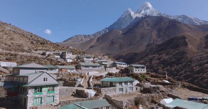 Drone flies over stone houses in Shomare village on the Everest Base Camp route, Nepal, revealing Ama Dablam in the distance. High-altitude residential settlement within the Himalayan landscape.