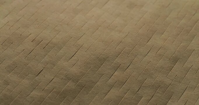 Brown Kraft Cardboard Texture with Diagonal Ridges. Gentle macro panning footage across a warm-toned ridged paper surface, highlighting parallel linear grooves and natural fiber patterns.