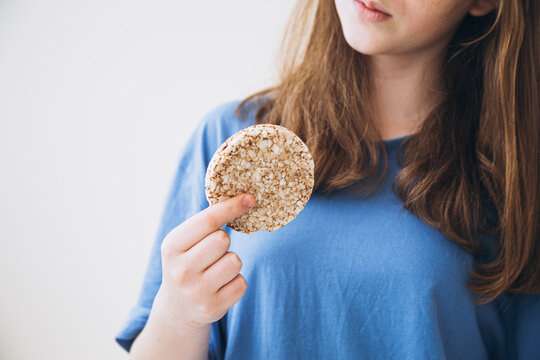 Whole grain cake, buckwheat cake, rice cake in the hands of a girl. Girl eating crunchy rice cake in her hands. Healthy food, healthy lifestyle. Copy space.
