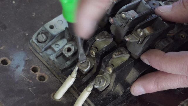 unscrew a screw on a terminal of old electrical equipment, repair of an electrical circuit breaker, unscrew an electrical aluminum wire with insulation