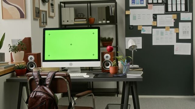 Medium full shot of computer with blank green template screen on work desk of UX engineer at mobile app development company, in office with wireframe layout designs on background wall