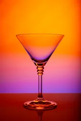 Minimalist martini glass against vibrant gradient backdrop, reflective surface, luxury cocktail stemware, modern bar design, clean studio photography, colorful nightlife mood © Regina