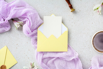 Yellow envelope with blank wedding invitation card inside on lilac gauze fabric