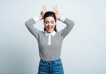 Playful woman making bunny ears and sticking her tongue out.