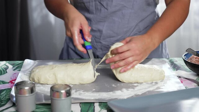 With a knife, the woman divides the dough into two parts, separates the ball and kneads it into a pancake. High quality 4k footage