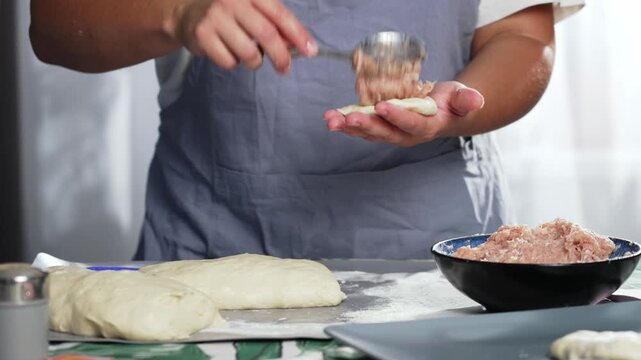 A woman uses a spoon to put minced meat on a round piece of dough and forms a pie. High quality 4k footage