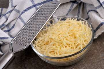 Ramequin de fromage r&acirc;p&eacute; avec une r&acirc;pe &agrave; fromage en gros plan