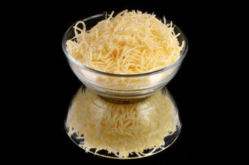 Ramequin de fromage r&acirc;p&eacute; en gros plan isol&eacute; sur fond noir avec son reflet