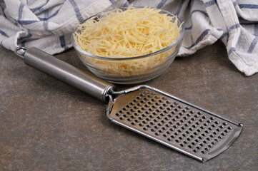 Ramequin de fromage r&acirc;p&eacute; avec une r&acirc;pe &agrave; fromage en gros plan sur fond gri