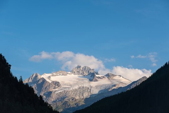 Snow-capped Alpine peak, part of the greater Mont Blanc range, towering over the Trient Valley. The rugged, glaciated summit striated with permanent ice and snow against a clear, deep blue sky.