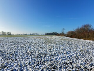 Borken, NRW, Germany, Winter landscape with snow covering a field under a clear blue sky.