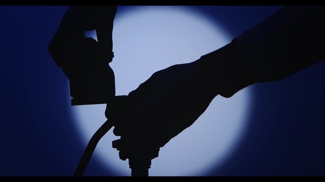 The operator sets up the platform and camera on a tripod in a dark studio with blue light, and a round white light from a spotlight in the center.