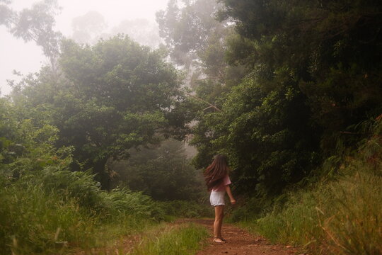 Lonely Woman Standing on Empty Curved Forest Road in Early Morning Fog, Concept of Slow Living.