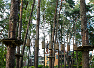 Fototapeta premium Active Boy Overcoming Rope Course Obstacles in Adventure Park