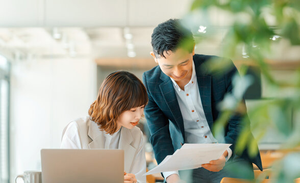 オフィスで資料を確認する上司と部下の打ち合わせシーン, Manager and junior staff reviewing documents together in office
