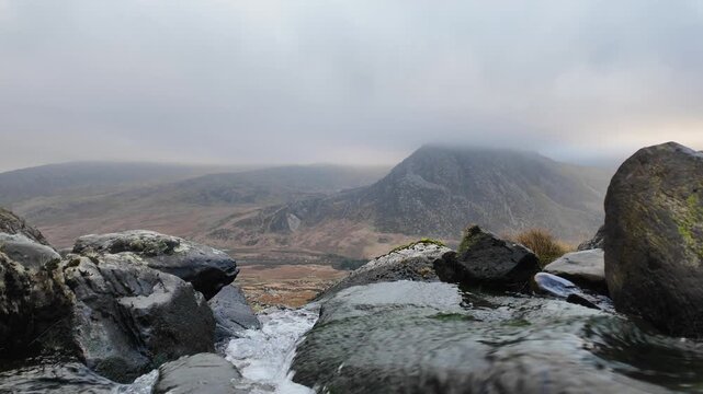 Misty mountain stream with rocky foreground