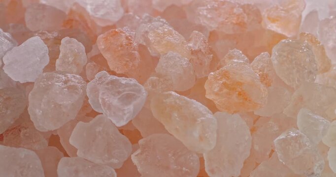 Pink Himalayan Salt Crystals Seamless Loop. Close-up macro view of coarse rose-colored Himalayan salt grains gently sparkling under soft lighting.