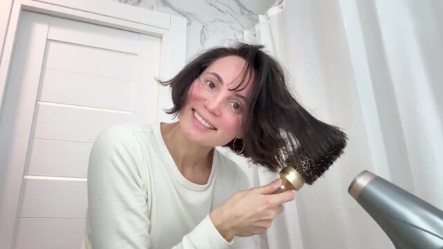 Smiled Woman with Messy Tangled Hair Brushing it with a Hair Dryer During Morning Routine