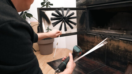 Man preparing to clean a modern indoor fireplace with a professional chimney brush.