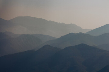 Fototapeta premium Romantic sunset over Italian city and mountains, warm golden light above urban landscape and countryside, travel and peaceful atmosphere
