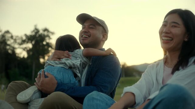 Family love moment of parents and their son together sitting at the park during sunset, people joyful family bonding moment filled with laughter playful and childhood in happy family time.
