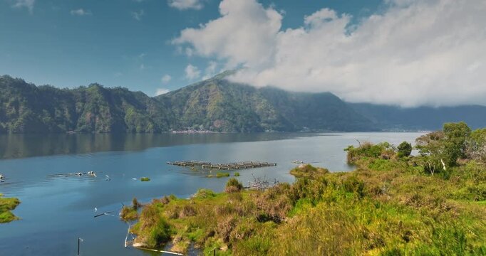 Mount Abang and Lake Batur with agricultural fields in Bali. Lush green terraced agriculture with traditional houses, tropical forest forming a serene landscape in Bali, Indonesia. Aerial view flight