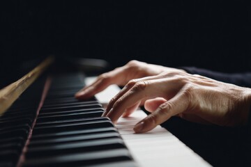 Obraz premium Close-up of caucasian female hands playing piano keys in low light