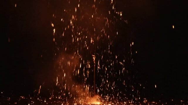 A single sparkler held aloft, emitting a bright white burst of light and sparks against a dark night sky, creating a starburst effect.