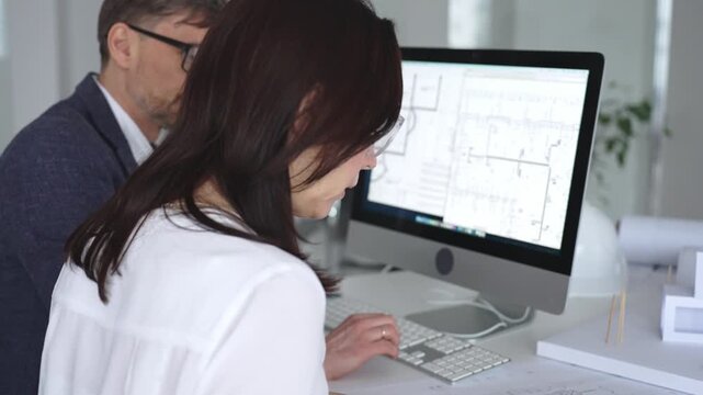 Architects collaborating on building plans using computer aided design software and architectural models. Business and architecture concept