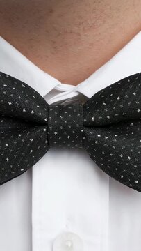 Vertical video: Filming man breathing, keeping black patterned bowtie centered at shirt collar