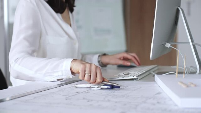 Architect creating new designs, working at a computer in office with blueprints and drafting tools. Business and architecture concept