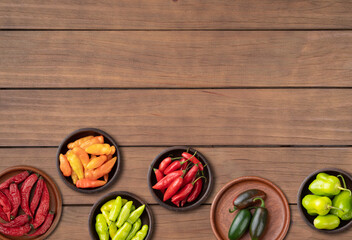 Assorted peppers over wooden table with copy space