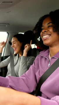 Happy female friends singing and dancing in car during road trip
